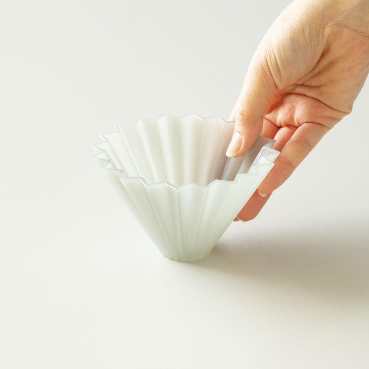 Der Origami Air Dripper in der Farbe Grey von vorne gehalten von einer Hand.